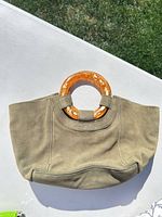 Front view of green suede handbag displaying resin handles