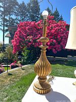 Full view of gold ribbed baluster lamp outdoors with harp and bulb attached