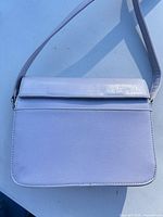 Front view of pale lavender shoulder bag showing flap and strap