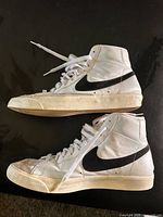 Side profile of both sneakers showing leather uppers and black Swoosh