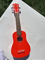 Full view of red Denver soprano ukulele on table