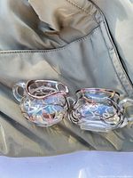 Creamer and sugar bowl showing silver overlay pattern and overall form