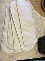 Stack of five white cotton terry cloth diaper inserts with rounded corners