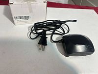 Air pump with cord and plug placed beside box, top view