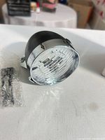 Side angle of black and chrome bullet motorcycle headlight with bubble-wrapped mounting screws
