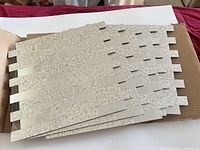 stack of mesh-backed ceramic mosaic tile sheets inside box