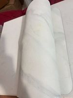 Mat rolled to show textured marble top surface and stains