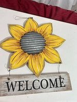 Front view of sunflower wall sign showing sunflower, metal center, WELCOME plank and wire loop