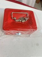 Top view of small red cash box with keys on lid