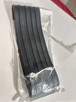 Sealed package containing black ribbed rubber strip showing top view