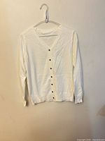 front view of white cardigan hanging on hanger