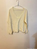 Front view of off-white V-neck knit sweater on hanger