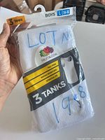 Front of sealed Fruit of the Loom package showing three white cotton tanks, size L 14-16