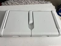Top view of white plastic monitor riser stand showing split lid and molded features