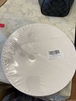 Top view of shrink-wrapped white round hat box with barcode label
