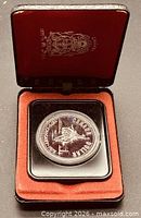 Coin in open presentation case showing capsule and red velvet interior