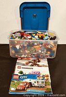 Front view showing open bin filled with assorted LEGO pieces and three instruction manuals
