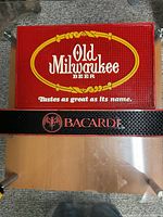 Old Milwaukee red rubber bar mat and Bacardi black rubber bar rail mat displayed on table