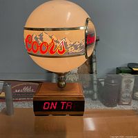 Front view of spherical Coors Light beer light on wooden base