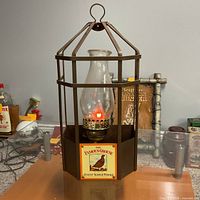 Front view showing Famous Grouse logo, glass chimney and red lit bulb