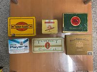 Six assorted vintage cigarette tins on a wooden surface