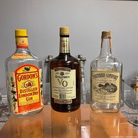 Front view of three empty 1.75 L liquor bottles: Gordon's Gin, Seagram's VO, Southern Comfort