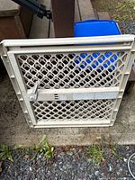 Front view of plastic expandable safety gate showing lattice panel and adjustment bar