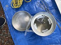 Aluminum pot with lid open, yellow nylon rope, stainless steel skewers on blue tarp
