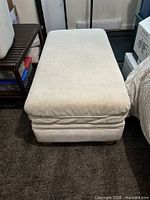 Top and front view of rectangular cream-beige ottoman on carpet