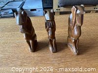Front view of three standing wood monkey figurines
