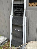 Aluminum folding ladder with black treads leaning against wall