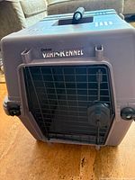 Front view showing Vari Kennel branding, metal wire door, twist latches, overall colour and condition