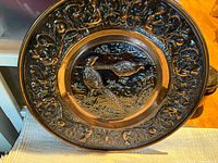 Front view of embossed copper wall plate with pheasant motif and ornate border