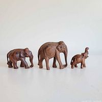 Three carved wooden elephant figurines lined up by size