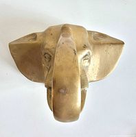 Front view of cast brass elephant head showing detailed features and trunk hook