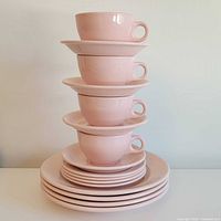 stacked pastel pink cups, saucers and plates