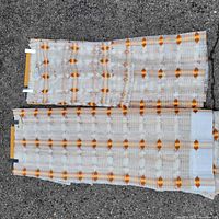 Two folded curtain panels laid flat, showing pattern and wood header strips