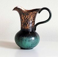 Profile view showing jug shape, hammered copper neck, patinated base