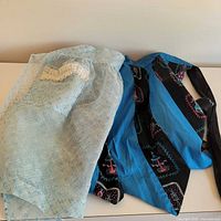 Two aprons laid out; sheer blue and paisley blue cotton visible