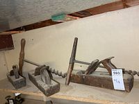 Full lot showing three wooden planes and two T-handle augers on shelf