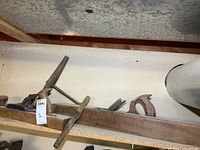 long wooden jointer plane, shorter plane, T-handle augers on shelf