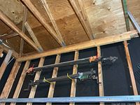 Two long bar clamps hung on wall studs