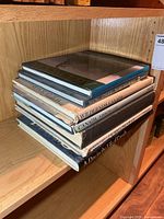 Stack of seven large hardcover books on shelf
