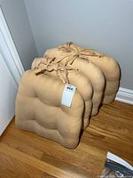 Four stacked beige seat cushions side view