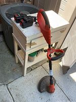 Full trimmer standing upright beside charger and two batteries on table