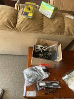 Lot overview with cardboard box of cables, sealed Jabra pack, sealed TP-Link box, loose bag of cords
