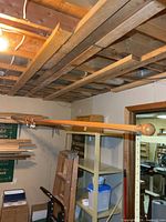 Full view of long solid wood tapestry rod mounted in basement ceiling bay