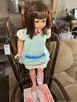 Full view of 34-inch plastic doll standing on chair