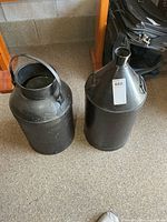 Both black metal milk cans side by side