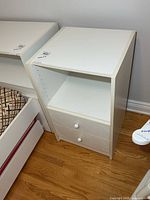 Front view of white melamine nightstand showing open shelf and two drawers